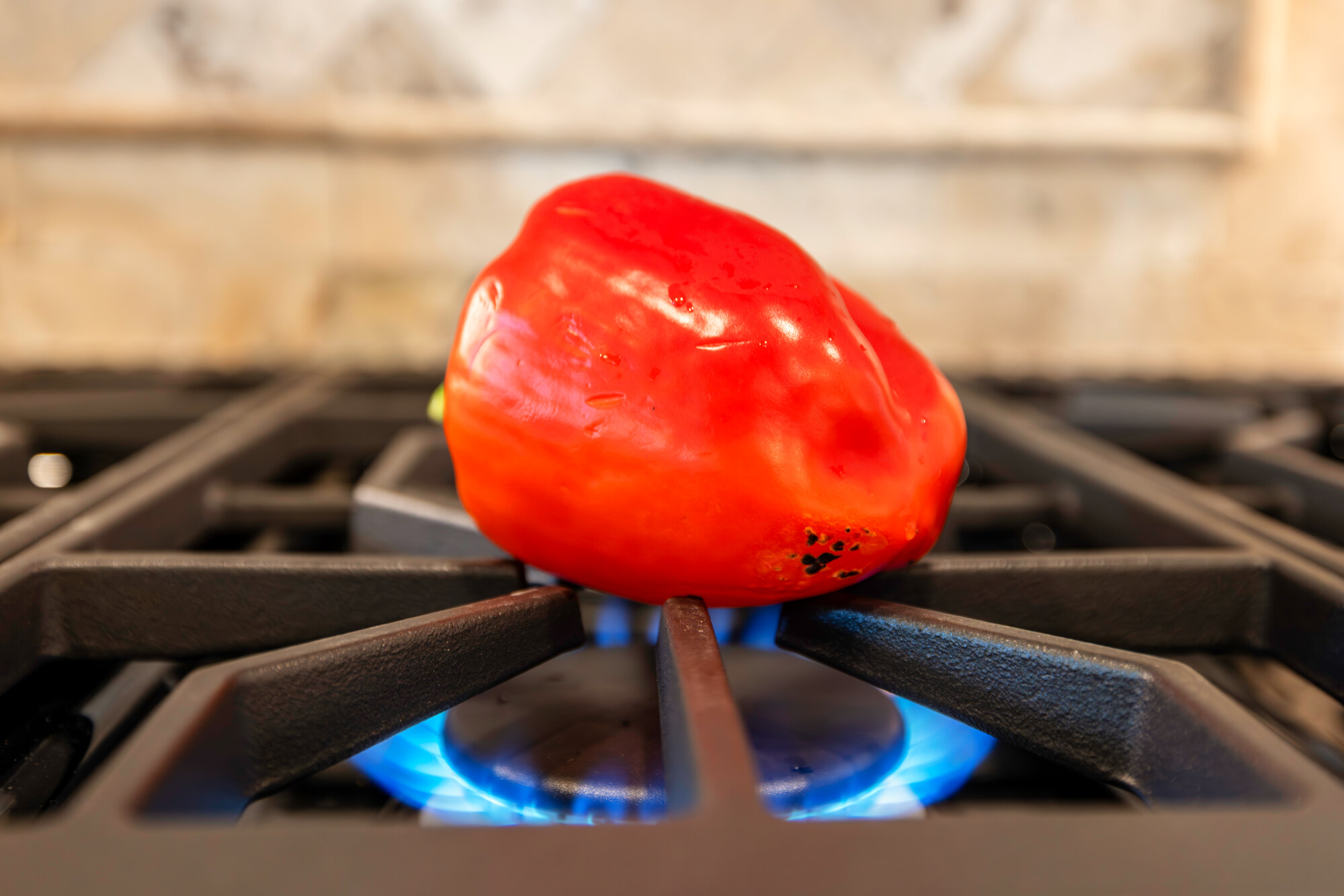 A pepper roasting over an open flame