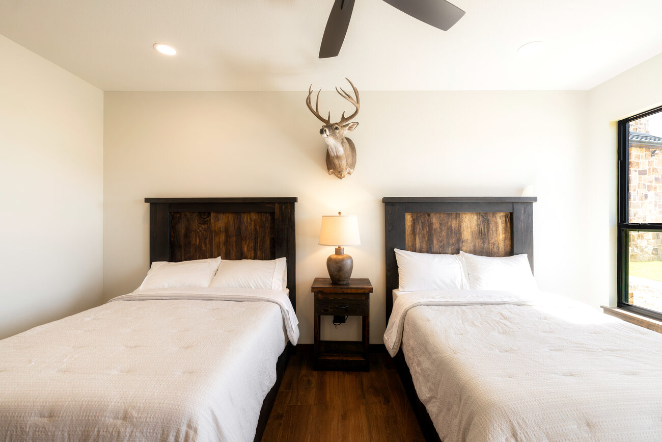 A bedroom with two beds and an antler mount